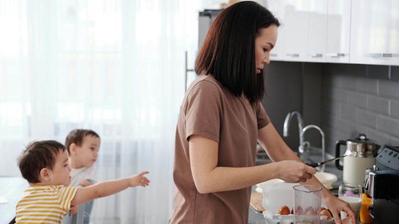 mãe cozinhando e cuidadndo e filhos pequenos